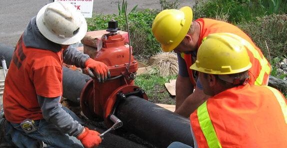 Repair workers completing valve insertion in a community's expansion project to provide water and sewer access